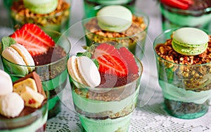 Trifles in plastic glasses with fresh fruit and cream.