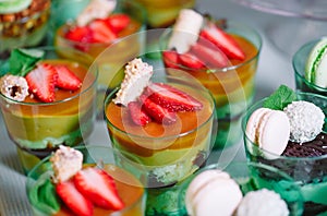 Trifles in plastic glasses with fresh fruit and cream.
