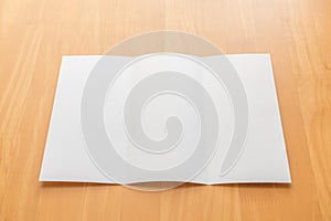 Trifold white template paper on wood background.