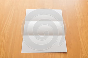 Trifold white template paper on wood background.