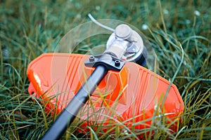 Trimmer close up mow grass with lawnmower.