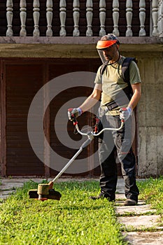 Trimmer in the hands of a man. Gardener cutting the grass