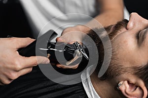 Trimming the beard with a shaving machine. Advertising for barbershop and men& x27;s beauty salon