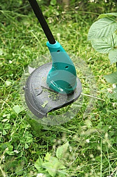 Trimming grass with an electric lawn trimmer