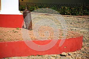 Trinidad city, Cuba. Sidewalk with an old rooted cannon on Calle Cristo, close-up