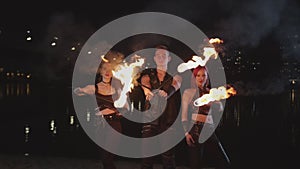 Trio of fireshow artists with lit torches by river