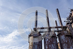 Trio of old blast furnaces and stacks against a blue sky with clouds