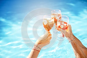 Trio traveler hands holding glass of cocktails on outdoor luxury swimming pool