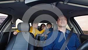 Trip with children, father with family in back seat wife with small male child and son in car seat drive in car