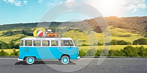 Trip with a van concept. The old, blue, hippie van is on road, luggage is on the roof