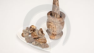 Triphala ayurvedic medicinal plant comprise of chebulic myrobalan fruit on white background with wood mortar and pestle