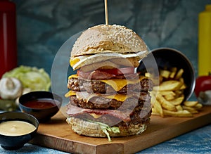 Triple burger with fries on a textured background