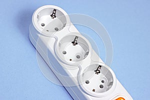 Triple socket white European power adapter with different wires at home. Standard electrical plug power outlet on blue background.