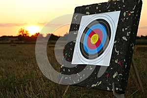 Tripod with archery target in field at sunset photo