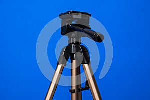 A tripod for a camera on a blue background is icholed. Equipment for photography