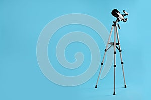 Tripod with modern telescope on light blue background, space for text