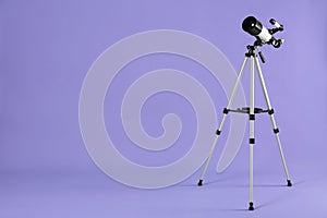 Tripod with modern telescope on light purple background, space for text