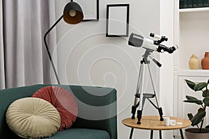 Tripod with modern telescope on table in living room