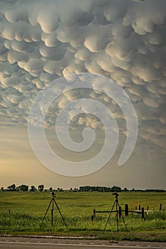 Tripods with equipment belonging to storm chasers below a thundery sky with mammatus clouds on the great plains.