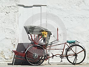 Trishaw parked at a white wall