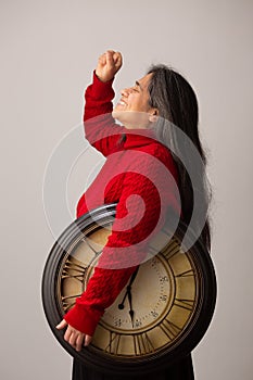 Triumphant Hispanic Woman Holding Clock Raises Fist Into The Air photo