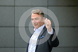 Triumphant stylish businessman giving a thumbs up gesture