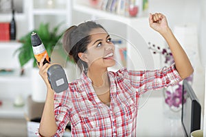 triumphant woman holding aloft cordless drill