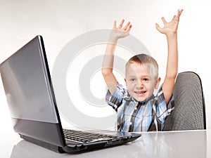 Triumphing child with a laptop computer isolated