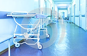 Trolley for patients in a long corridor of modern hospital. Surgical department. Blue toning