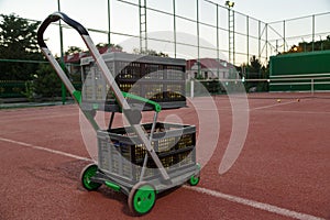 Trolley for tennis balls on the tennis court in the evening