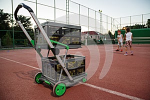 Trolley for tennis balls on the tennis court in the evening