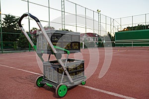 Trolley for tennis balls on the tennis court in the evening