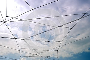 Trolleybus wires against a blue sky with white clouds