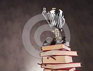 Trophy cup award and glasses on top of books