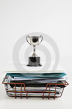 Trophy over stack of folders against white background