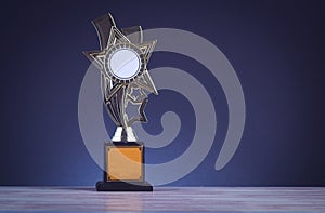 Trophy placed on wooden table over dark background