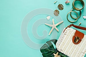 Tropic flat lay with straw hat, bag, starfish, shells, sunglasses, boat, earrings on green background. Summer fashion flat lay