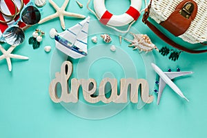 Tropic flat lay with wooden word Dream starfish, shells, sunglasses, boat, earrings on green background. Summer fashion flat lay