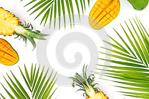Tropic frame of pineapple and mango fruits with palm leaves on white background. Flat lay