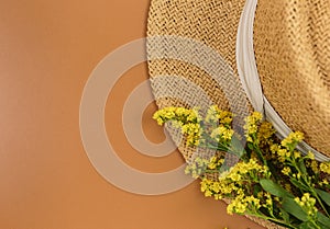 Tropic leaves, straw hat on brown background. Trendy fashion accessories. Flat lay, close up. Summer, vacation, holidays concept.