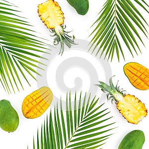 Tropic pattern of pineapple and mango fruits with palm leaves on white background. Flat lay