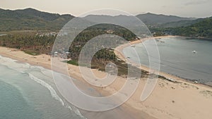 Tropic resort with tourists at sand beach aerial. Ocean coast with resort and lodges buildings