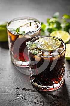 Tropical alcoholic cocktail Cuba Libre composed of white rum, cola, ice cubes, lime and mint