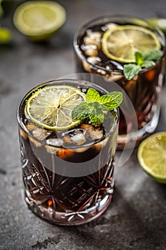 Tropical alcoholic cocktail Cuba Libre composed of white rum, cola, ice cubes, lime and mint