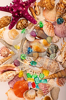 Tropical background of beautiful shells on a white background. Scattered seashells, starfis, emeralds and gems. Tropical