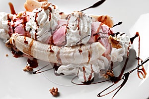 Tropical banana split with chocolate drizzle over three scoops of chocolate, strawberry and vanilla ice cream on fresh