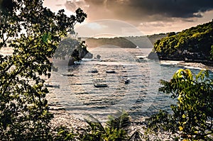 Tropical bay landscape with blue sea and small fishing boats. Exotic island landscape before sunset viewed from a hill overlooking