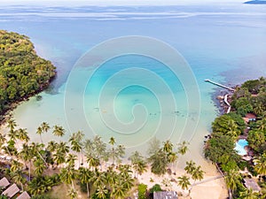 Tropical beach aerial view from drone with blue transparent sea water and coconut palm trees, seaside tourist hotel resort with