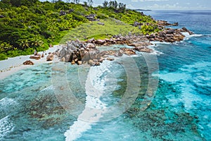 Tropical beach Anse Cocos. La Digue island. Seychelles. Drone aerial view of coastline with blue ocean waves, unique