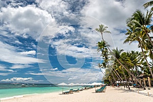 Tropical beach background from Alona Beach at Panglao Bohol island with Beach chairs on the white sand beach with cloudy blue sky photo